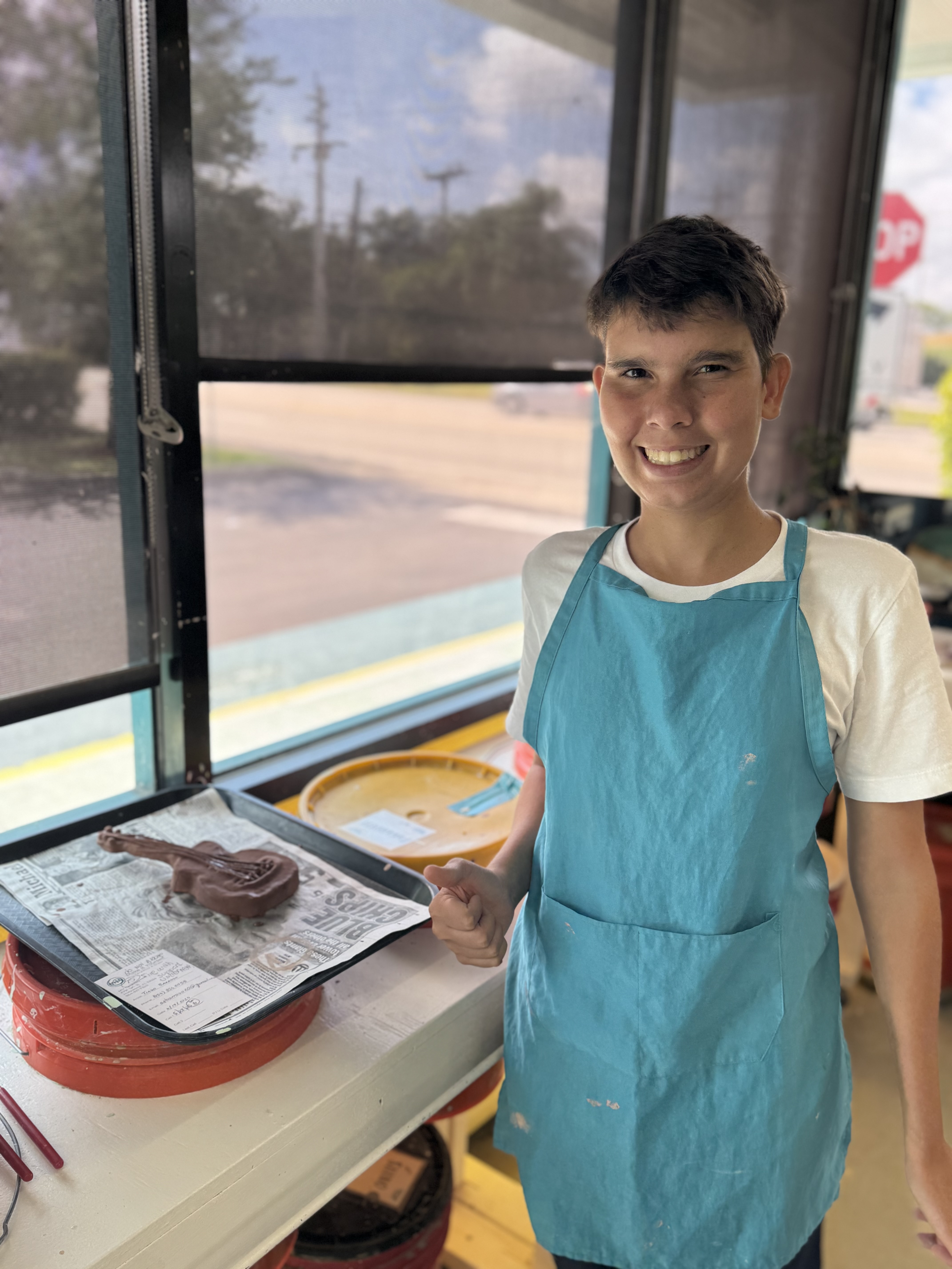 Tiago Barroso in his ceramics studio, smiling with clay and tools on the table