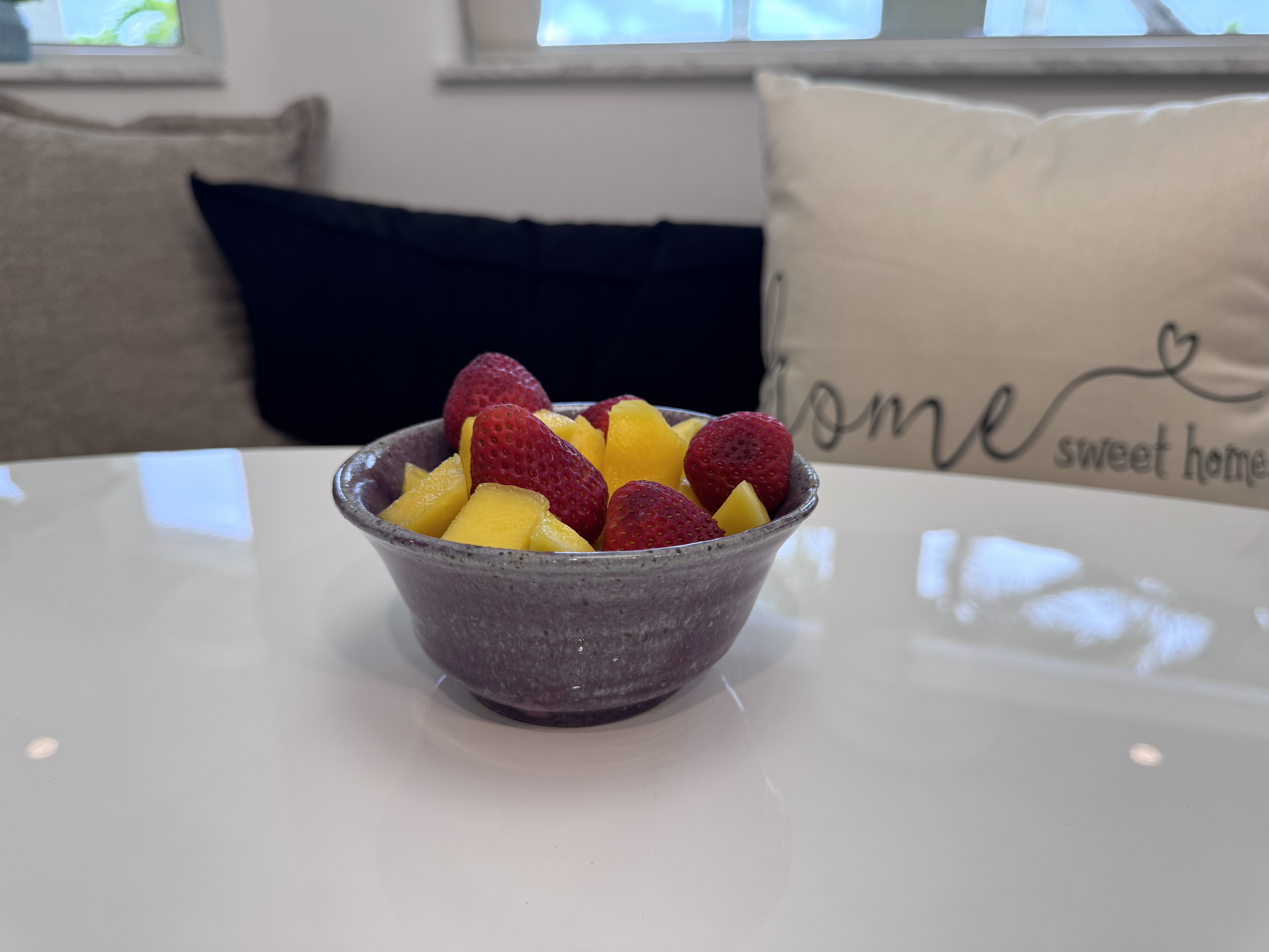 Handmade ceramic bowl with lavender glaze, filled with fresh fruit