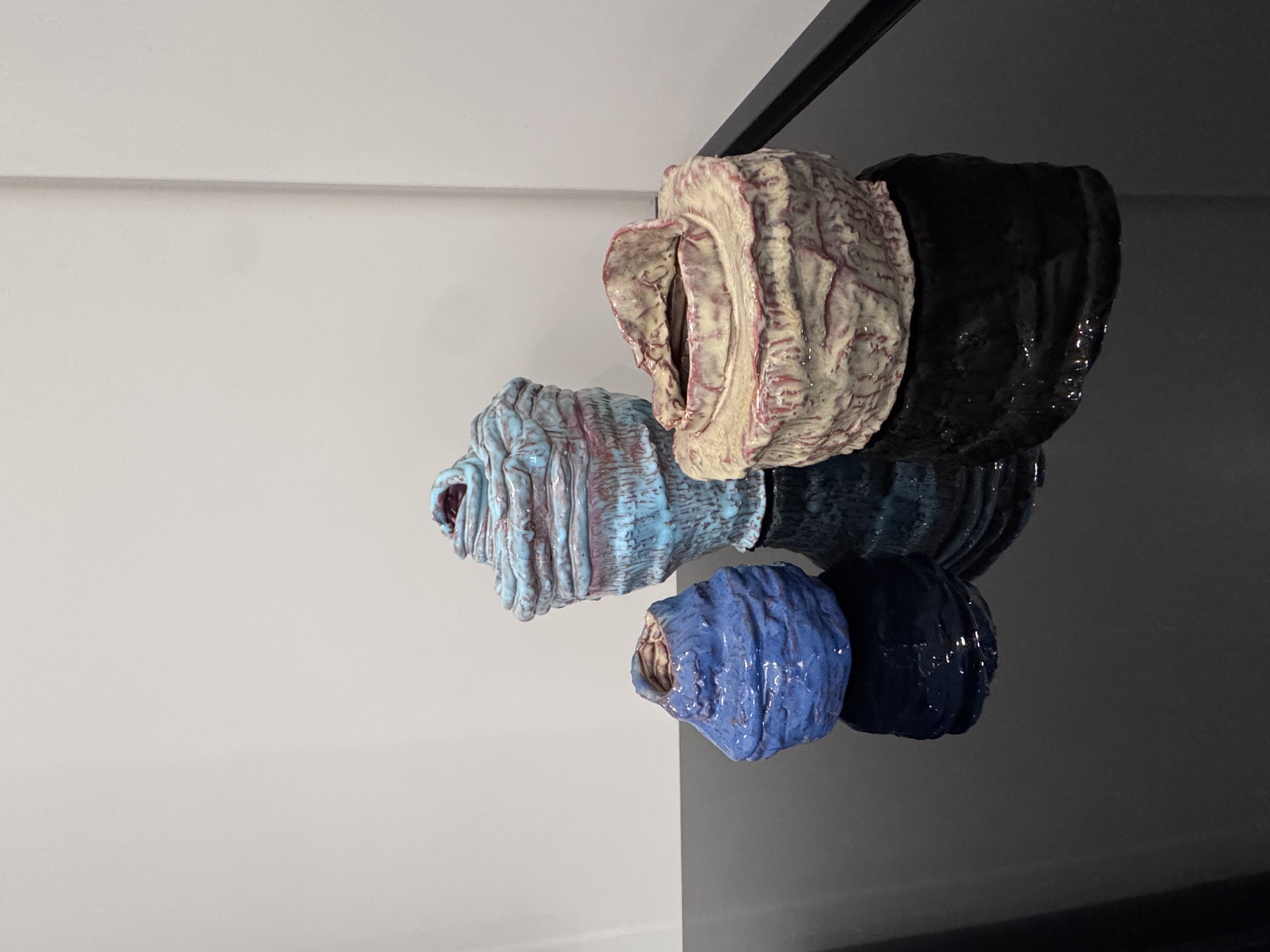 Handmade coil jars with textured glazes in blue, pink, and black